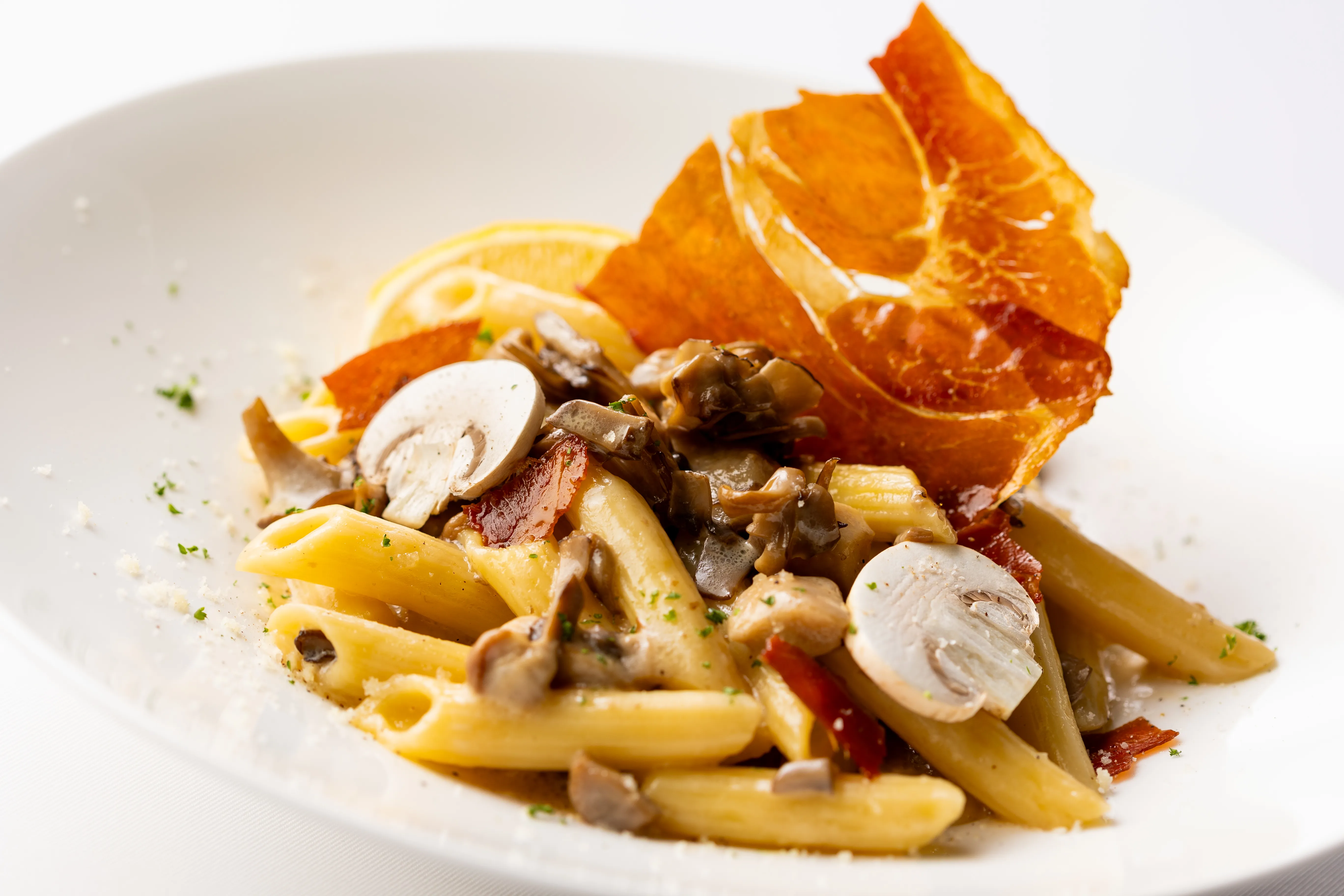 Cream Penne With Four Types Of Mushrooms And Prosciutto Garnished With Lemon