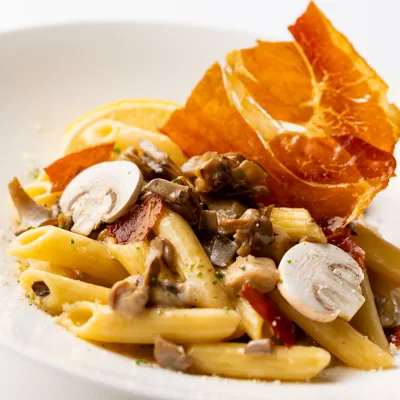 Cream Penne With Four Types Of Mushrooms And Prosciutto Garnished With Lemon